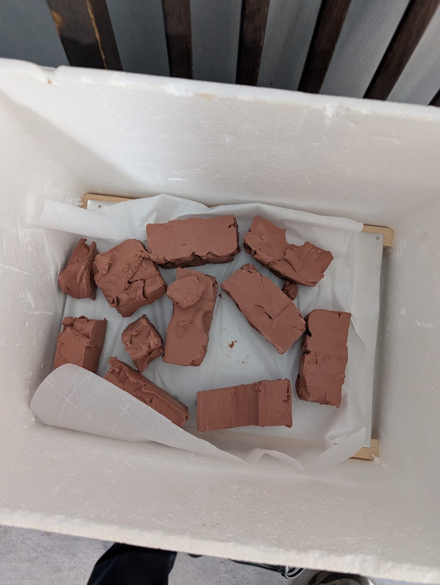 Slabs of oil clay on baking parchment inside a polystyrene box